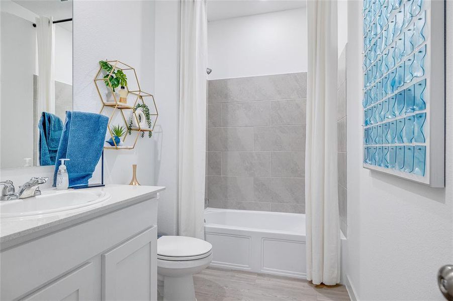 Full bathroom with shower / bathtub combination with curtain, vanity, hardwood / wood-style flooring, and toilet