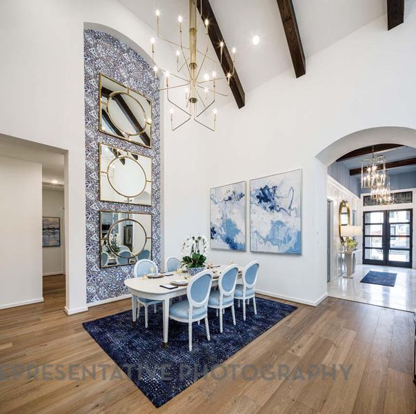 Dining space with a chandelier, a high ceiling, arched walkways, beam ceiling, and wood finished floors Dining space with a chandelier, a high ceiling, arched walkways, beam ceiling, and wood finished floors