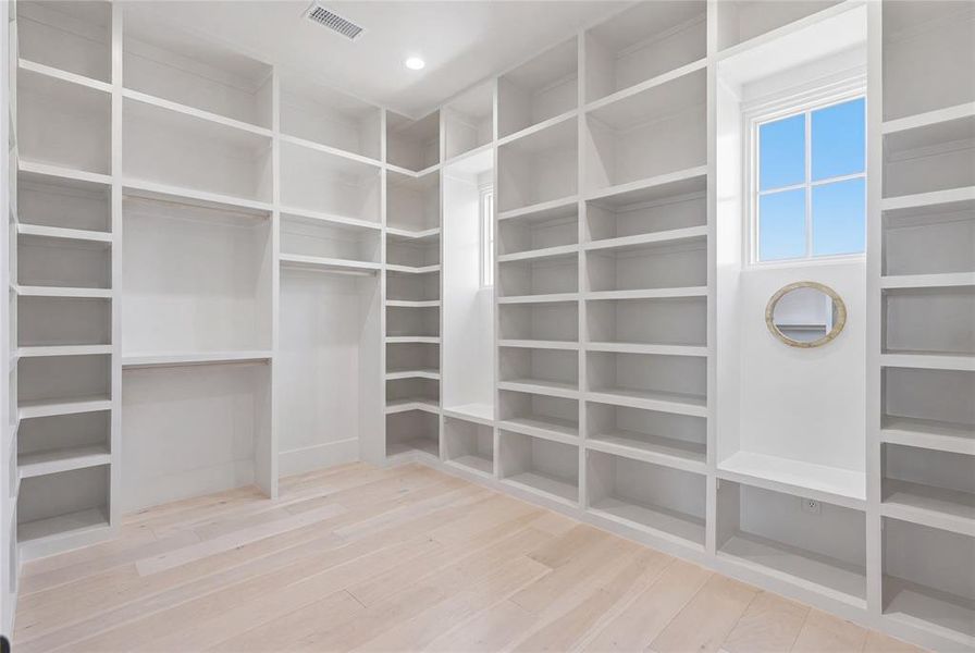 Expansive custom built-in shelving system with light wood-finish flooring