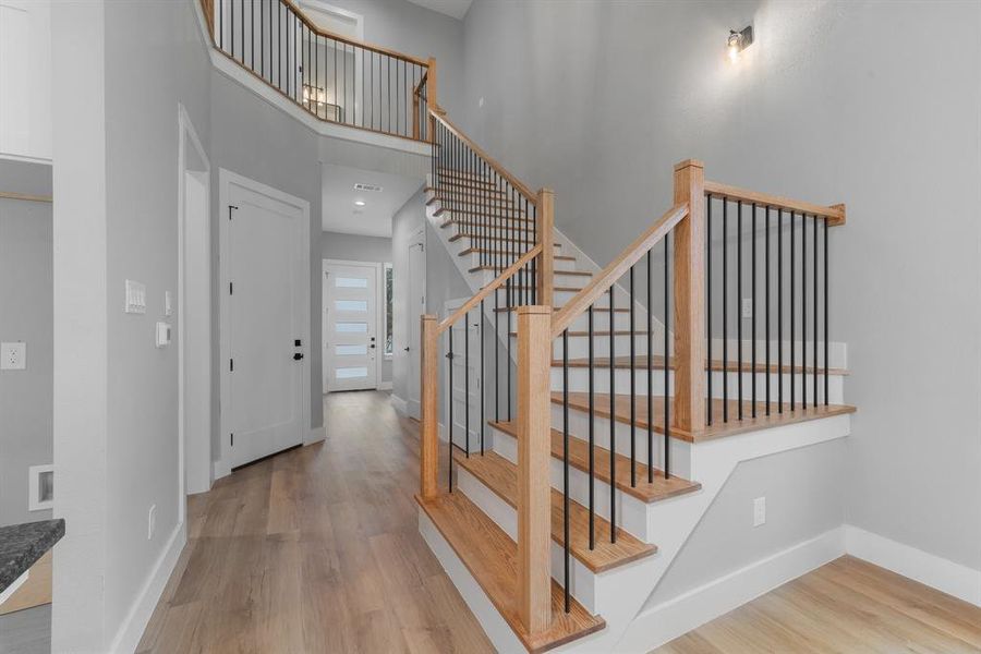 Stairway with visible vents, baseboards, a high ceiling, and wood finished floors