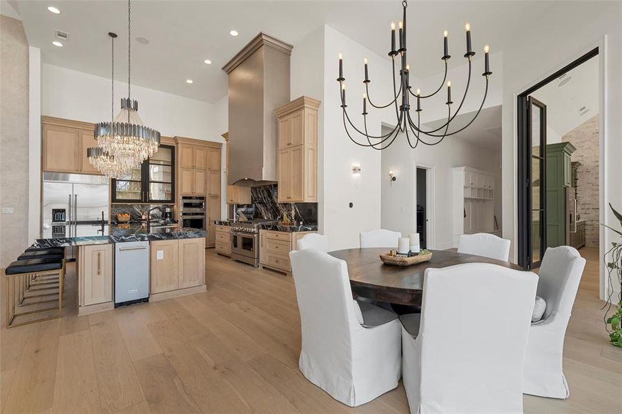 Dining area with a chandelier, a high ceiling, light wood-style flooring, and recessed lighting