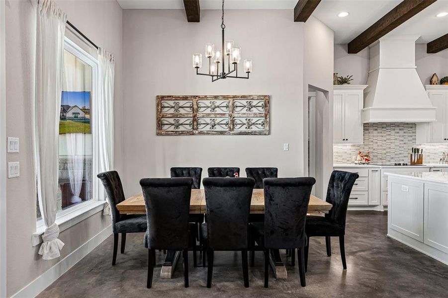 Dining room with concrete floors, a chandelier, and beam ceiling Dining room with concrete floors, a chandelier, and beam ceiling