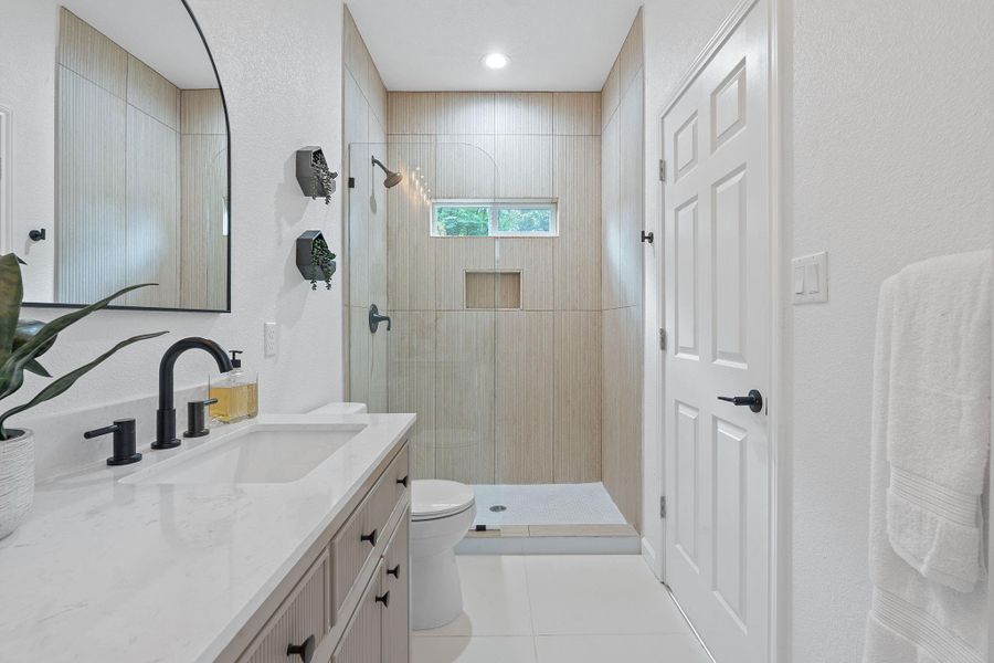 Full bath with vanity, a walk in shower, and tile patterned floors