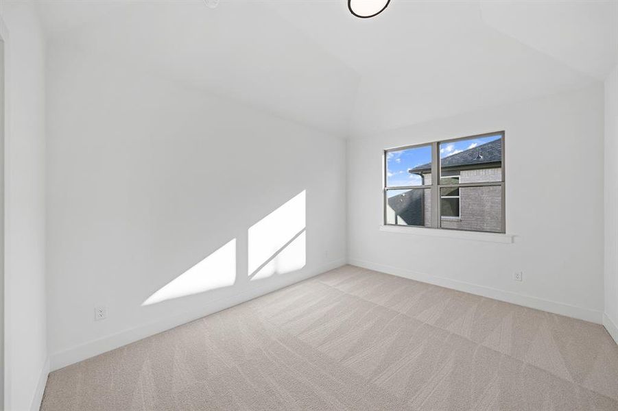 Spare room featuring light carpet and lofted ceiling