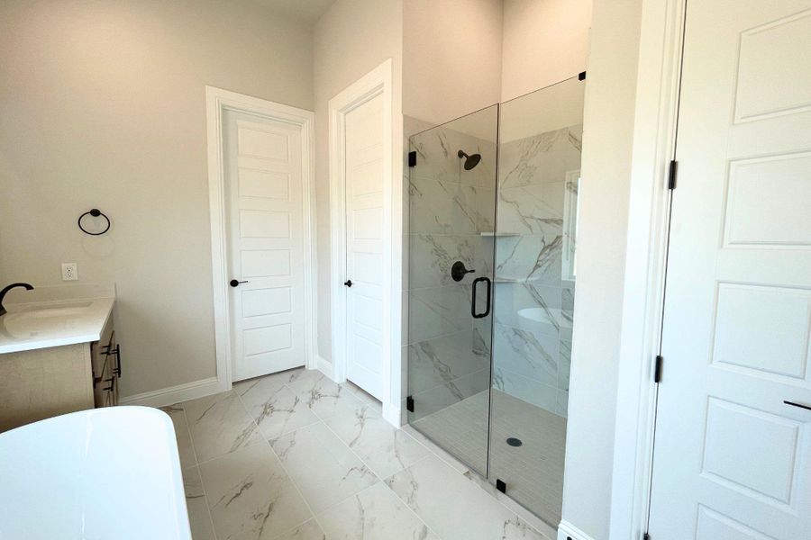 Sleek marble-patterned tile floors and a glass-enclosed shower highlight this modern bathroom design. Sleek marble-patterned tile floors and a glass-enclosed shower highlight this modern bathroom design.