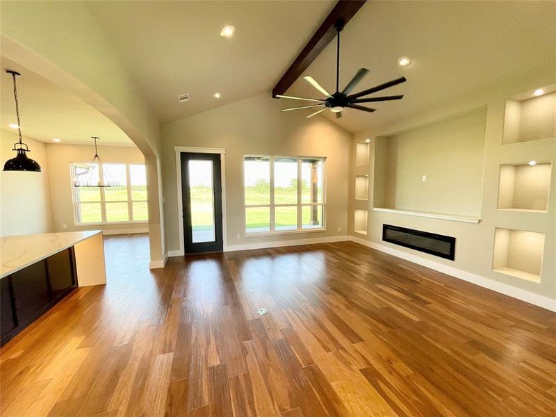 Unfurnished living room featuring hardwood / wood-style flooring, a healthy amount of sunlight, beamed ceiling, and built in features