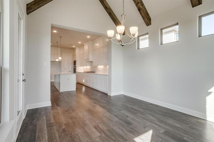 Unfurnished dining area featuring dark hardwood / wood-style flooring, beamed ceiling, sink, and plenty of natural light