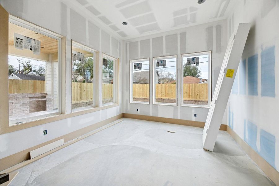 Positioned between the kitchen and living areas, the dining space is wrapped in large windows that bring in abundant natural light. Sightlines extend to the covered patio and backyard, making the room feel open and connected while providing an inviting backdrop for gatherings and daily dining.