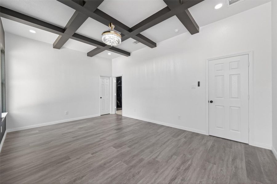 Luxurious primary bedroom featuring generous space, abundant natural light, and stunning custom wood ceiling beams that add warmth, character, and an elegant designer touch.