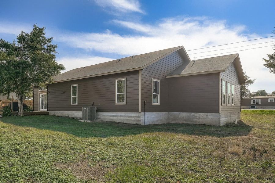 View of side of property featuring a lawn and a cooling unit View of side of property featuring a lawn and a cooling unit