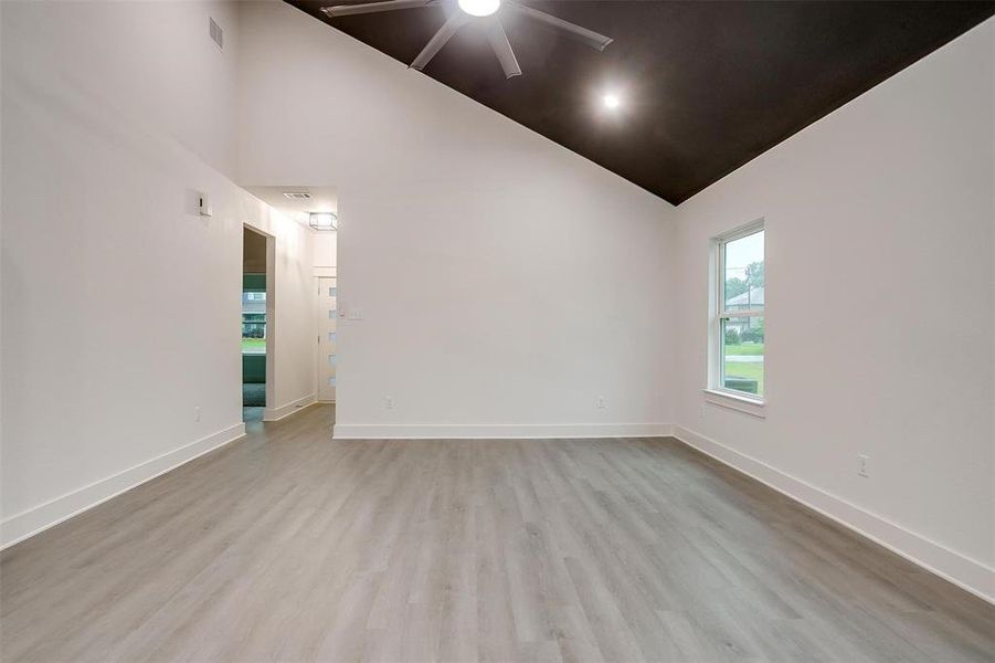 Empty room featuring high vaulted ceiling, ceiling fan, and wood finished floors