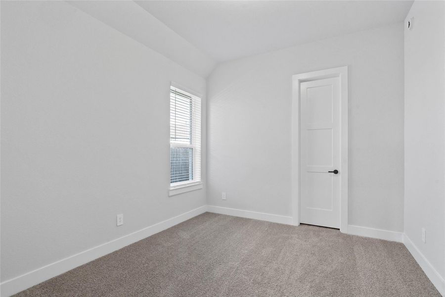 This cozy secondary bedroom offers plush soft carpeting, neutral walls ready for personalization, sun-filled window, sloped ceilings, and a walk-in closet.