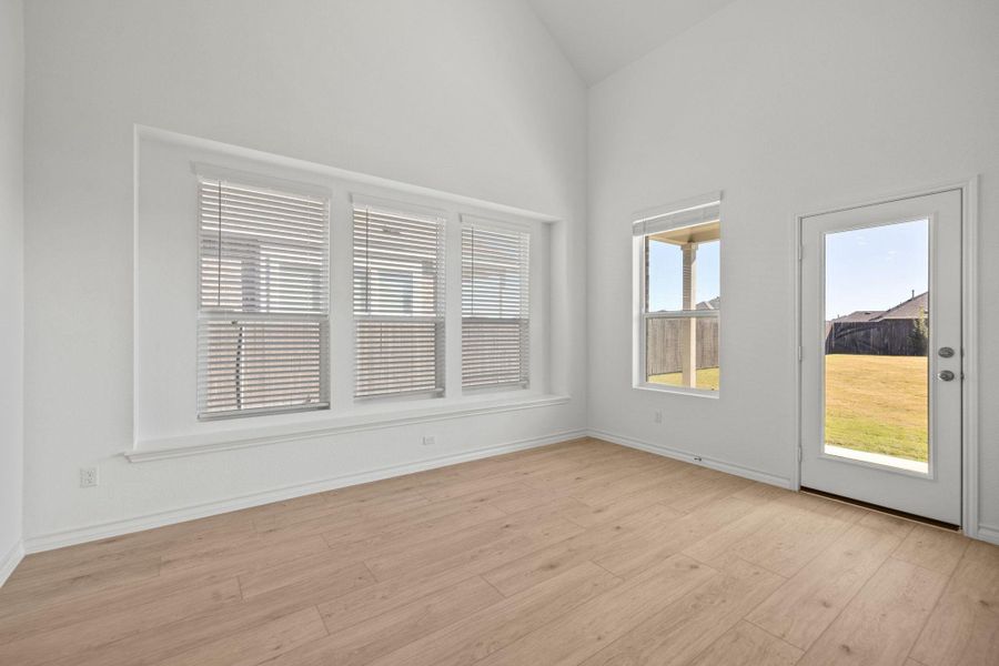 Unfurnished room with light wood-style floors and vaulted ceiling