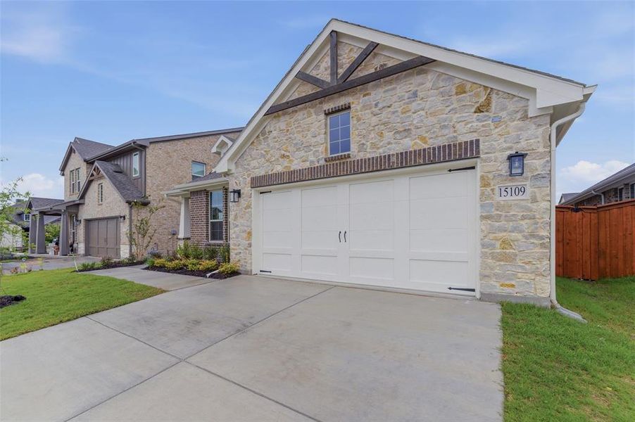 Stone and brick exterior featuring a white two-car garage door with decorative hardware