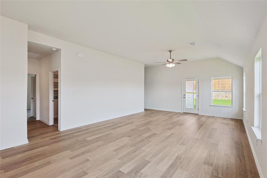 Empty room with ceiling fan, vaulted ceiling, and light hardwood / wood-style flooring