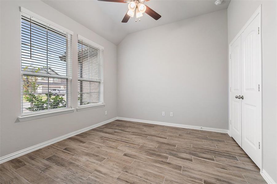 Unfurnished bedroom featuring wood finish floors, lofted ceiling, a ceiling fan, and a closet Unfurnished bedroom featuring wood finish floors, lofted ceiling, a ceiling fan, and a closet