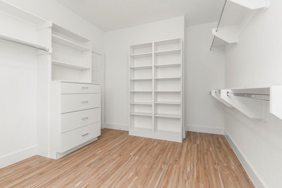 Designed for effortless organization, this walk-in closet features sleek laminate flooring, built-in shelves and drawers, plus ample hanging space for a streamlined wardrobe.