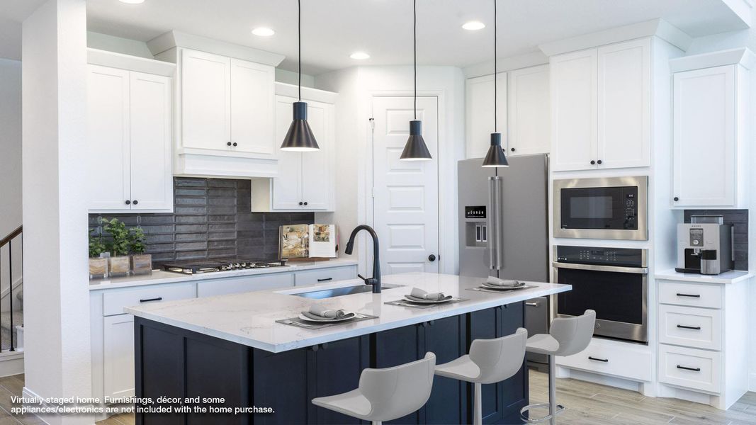 Kitchen with light wood-style flooring, decorative backsplash, light stone countertops, stainless steel appliances, and a kitchen island with sink