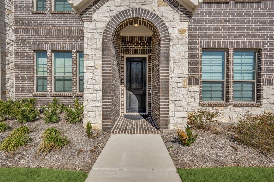 Doorway to property featuring brick siding and stone siding