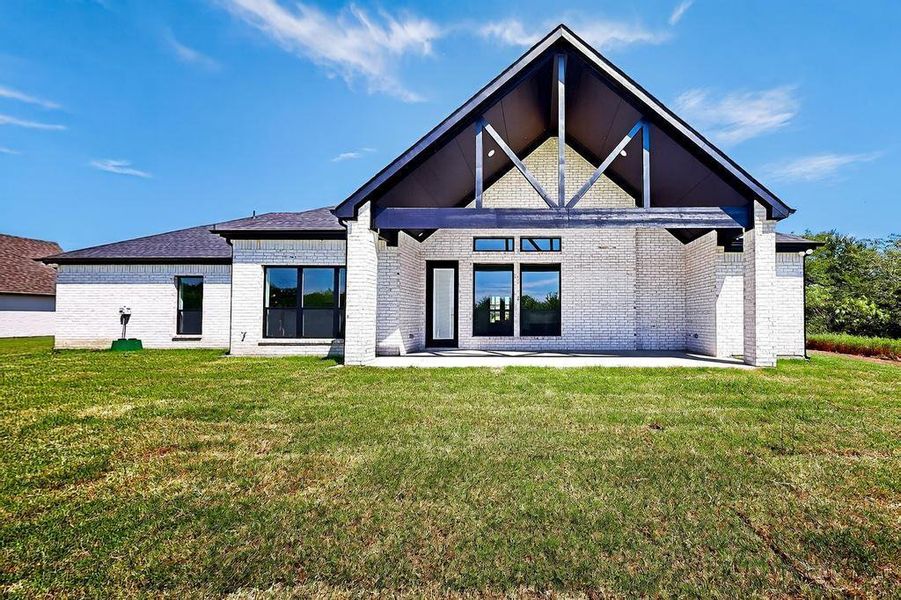 Back of property with a patio, brick siding, and a lawn