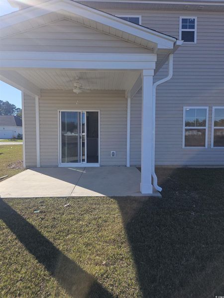 View of exterior entry featuring ceiling fan, a patio area, and a yard
