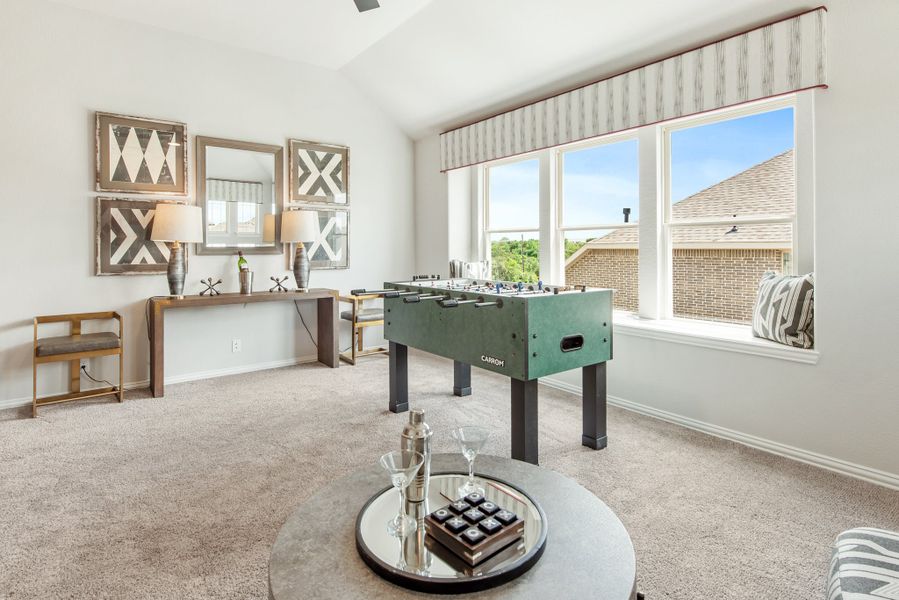 Game room with foosball table, carpet flooring, vaulted ceiling, and large windows Game room with foosball table, carpet flooring, vaulted ceiling, and large windows