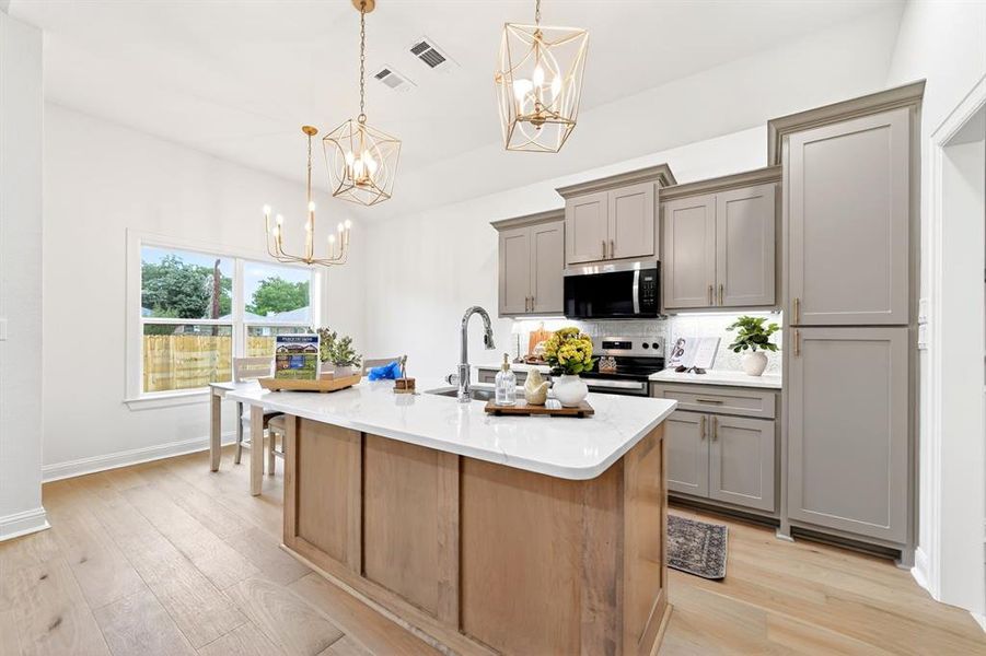Spacious kitchen featuring a large central island with a light wood finish, white countertop, and integrated sink