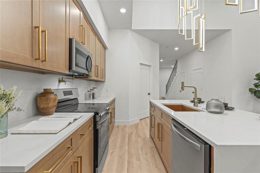 Kitchen featuring stainless steel appliances, a sink, light wood-type flooring, recessed lighting, and light stone counters Kitchen featuring stainless steel appliances, a sink, light wood-type flooring, recessed lighting, and light stone counters