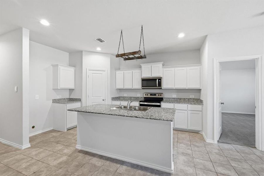 Kitchen featuring white cabinets, stainless steel appliances, light stone counters, a center island with sink, and recessed lighting Kitchen featuring white cabinets, stainless steel appliances, light stone counters, a center island with sink, and recessed lighting