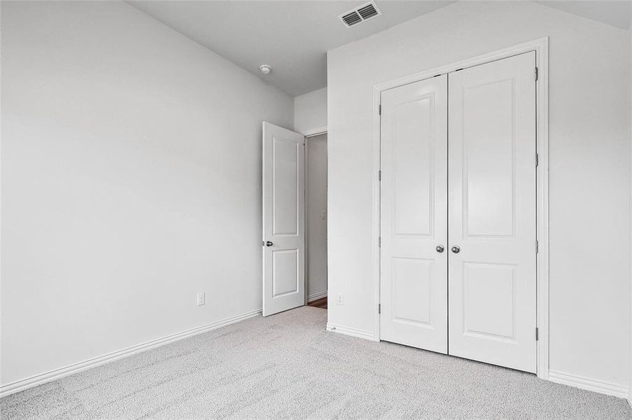 Unfurnished bedroom featuring light carpet and a closet