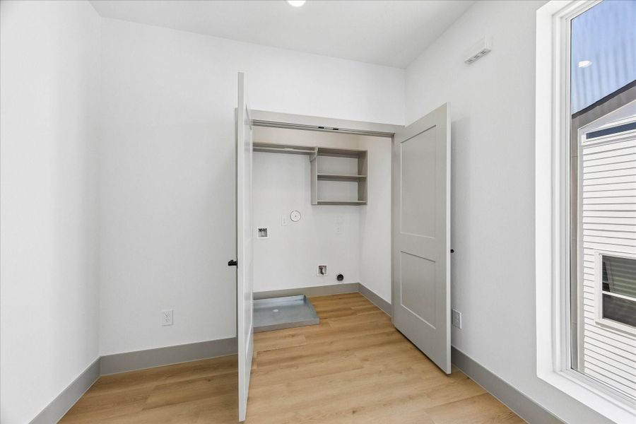 Dedicated laundry room with built in shelving offers practical storage and everyday convenience just steps from the bedrooms.
