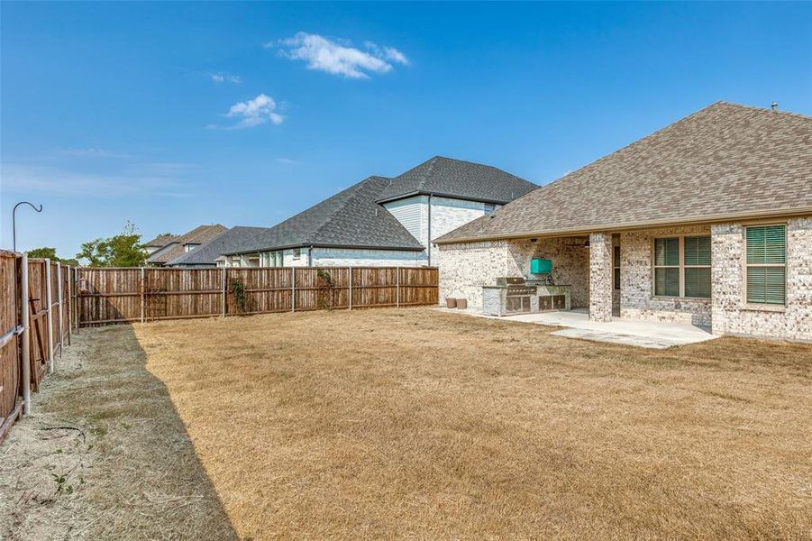 Fenced backyard featuring an outdoor kitchen and a patio Fenced backyard featuring an outdoor kitchen and a patio