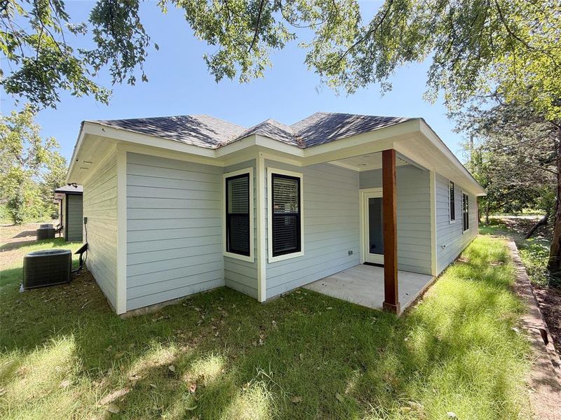 View of home's exterior with a patio area, a lawn, and roof with shingles