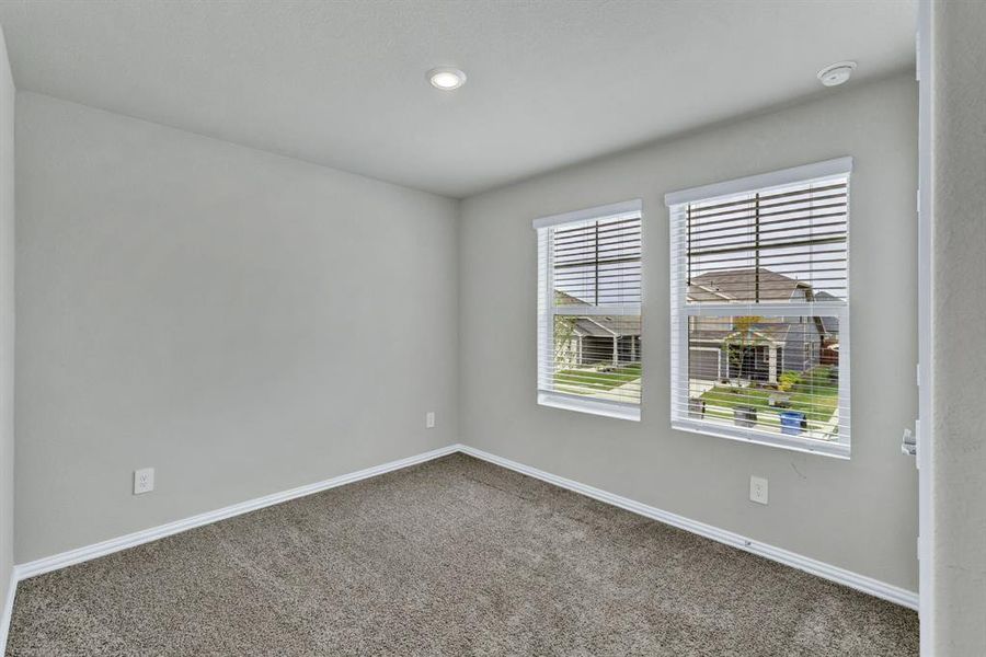 This room features light grey walls, carpeted flooring, and two windows with blinds