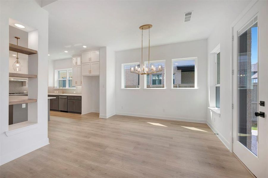 Unfurnished dining area featuring light wood-style flooring and suspended lighting
