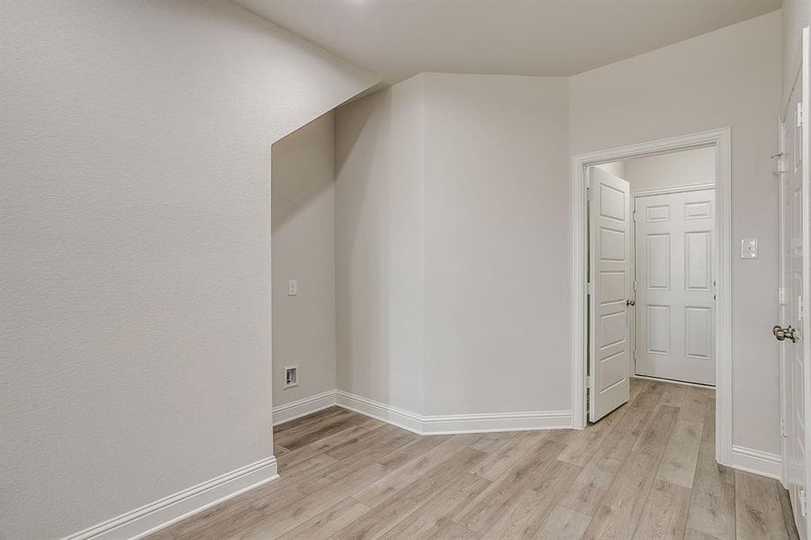 Additional living space with light wood-style floors and baseboards