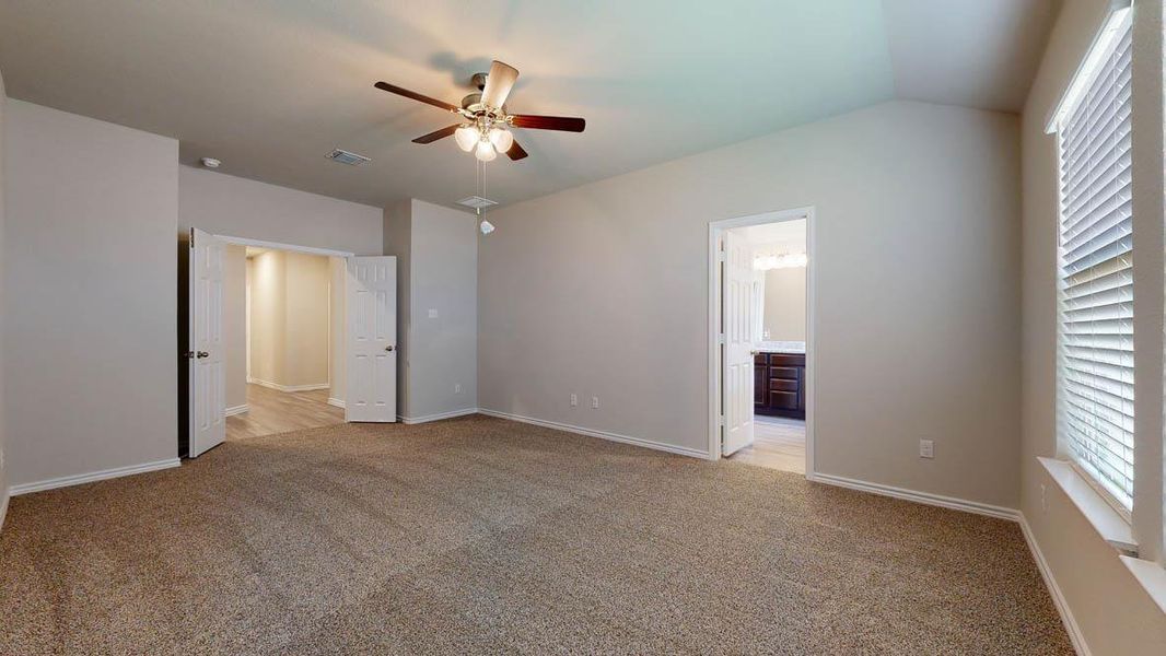 Carpeted room with vaulted ceiling and a ceiling fan with integrated lighting