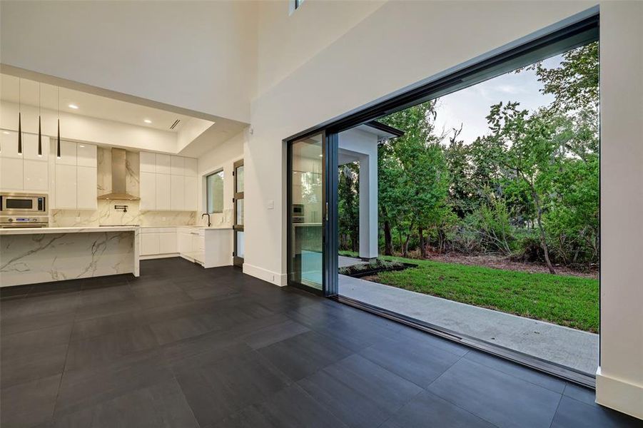 The boundaries between indoor and outdoor living blur effortlessly through sliding glass doors, revealing a private oasis of lush landscaping and a glistening pool.