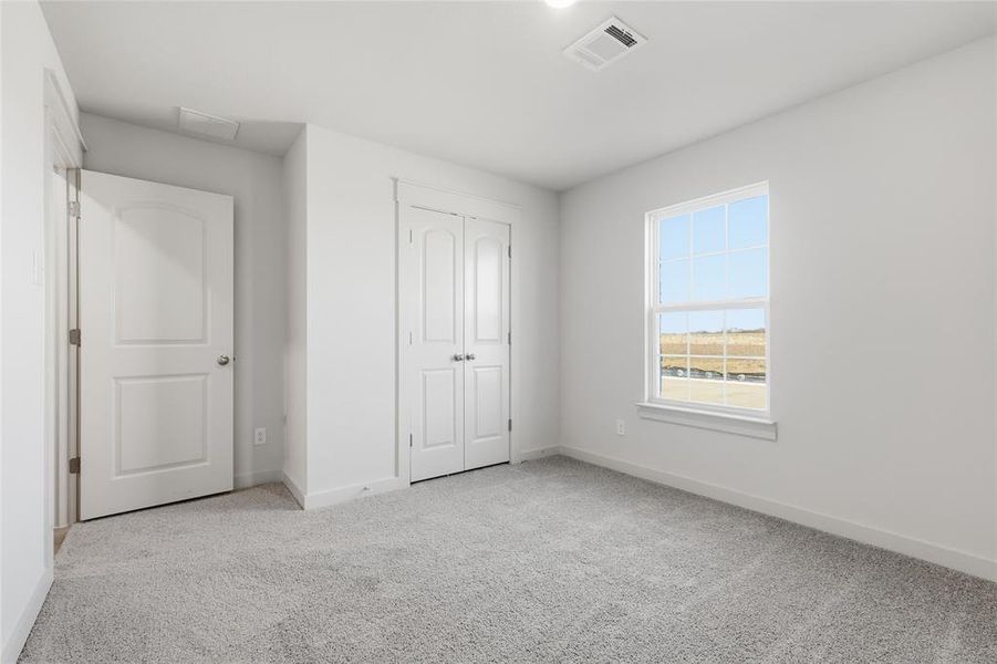 Unfurnished bedroom with light colored carpet and a closet