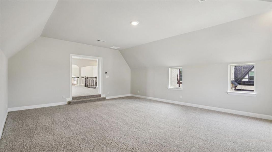 Bonus room with lofted ceiling, light carpet, and plenty of natural light Bonus room with lofted ceiling, light carpet, and plenty of natural light
