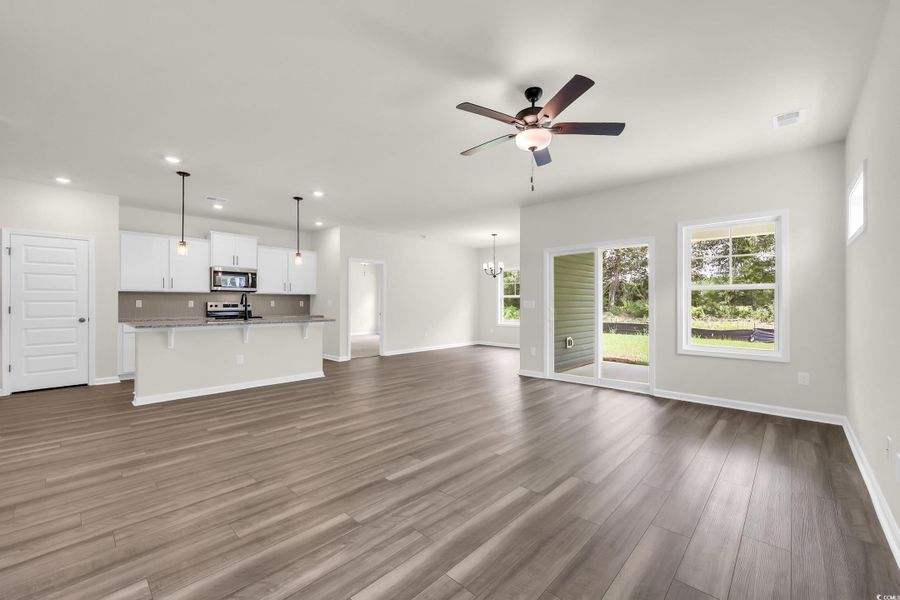 Unfurnished living room featuring a chandelier, dark wood-style floors, a ceiling fan, and recessed lighting
