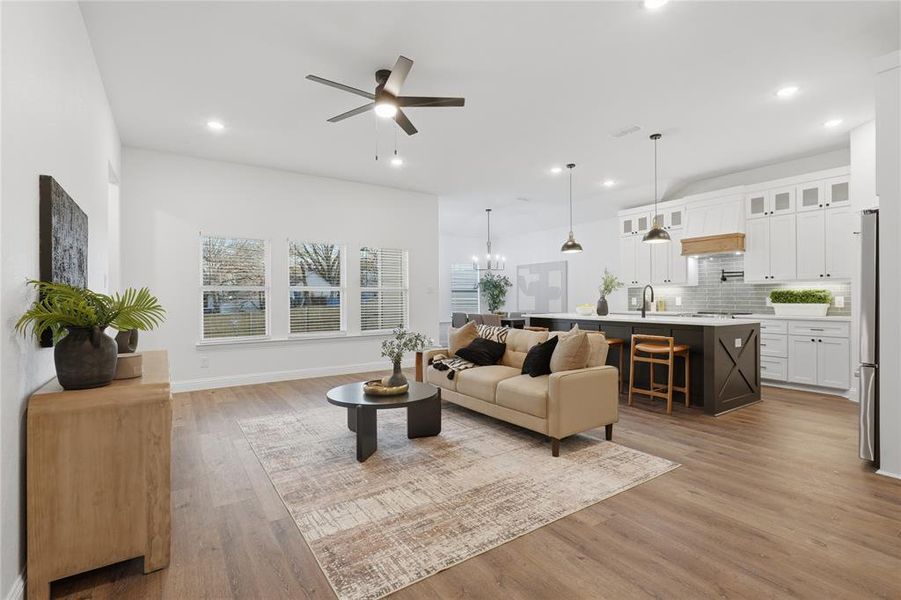 Living room featuring a chandelier, a ceiling fan, and light wood-style floors