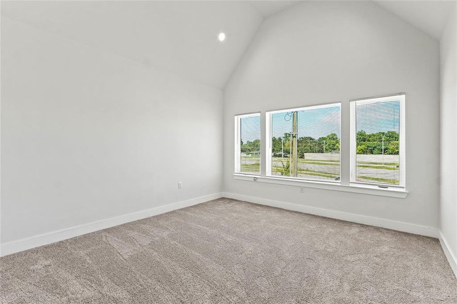 Empty room with high vaulted ceiling, light colored carpet, and recessed lighting Empty room with high vaulted ceiling, light colored carpet, and recessed lighting