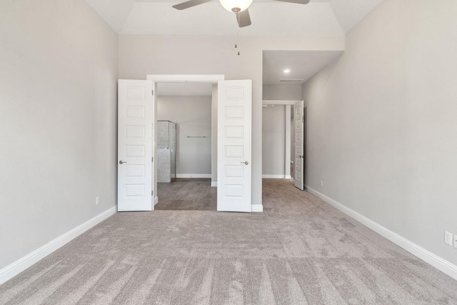 Unfurnished bedroom featuring carpet flooring, ceiling fan, baseboards, and vaulted ceiling Unfurnished bedroom featuring carpet flooring, ceiling fan, baseboards, and vaulted ceiling