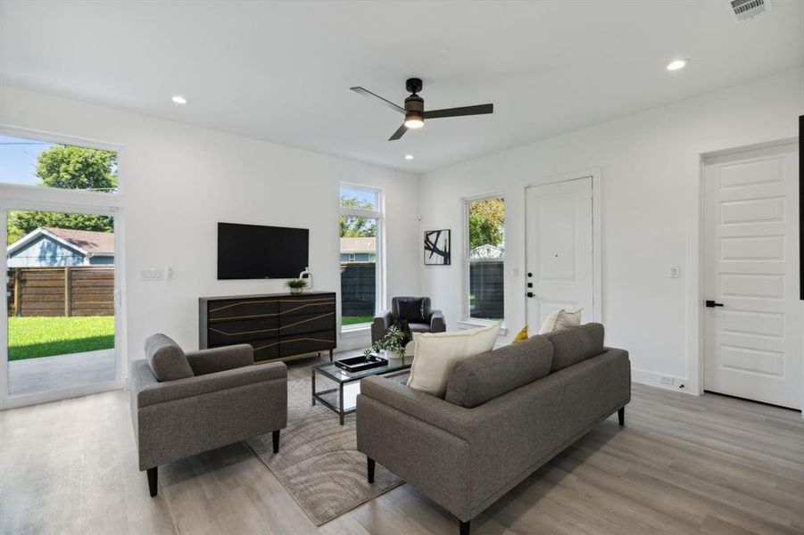 Living room with ceiling fan, light hardwood / wood-style floors, and a wealth of natural light