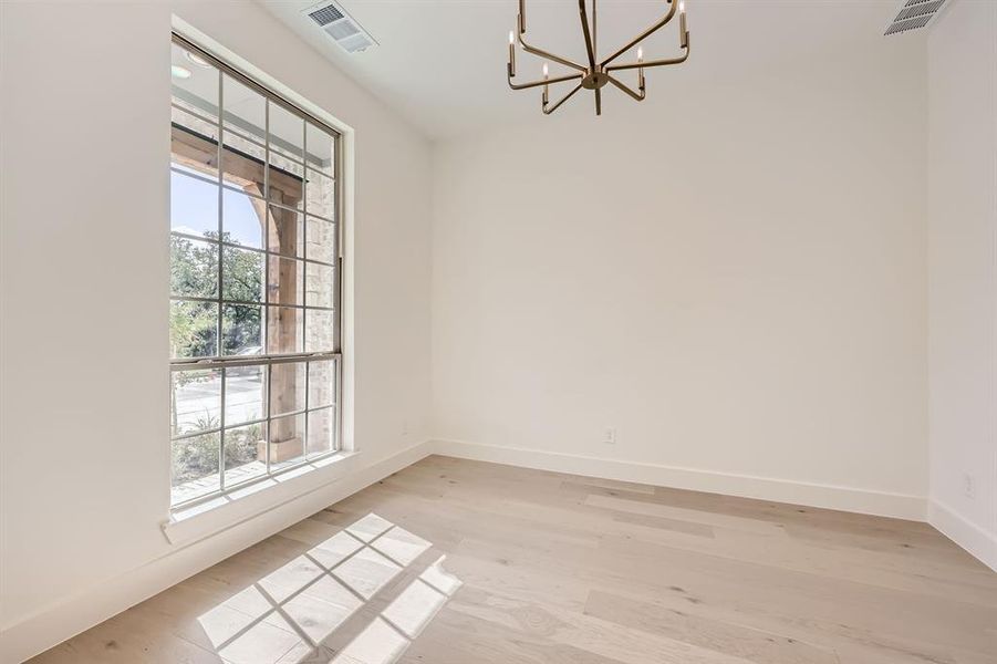 Empty room with light hardwood / wood-style floors and a chandelier