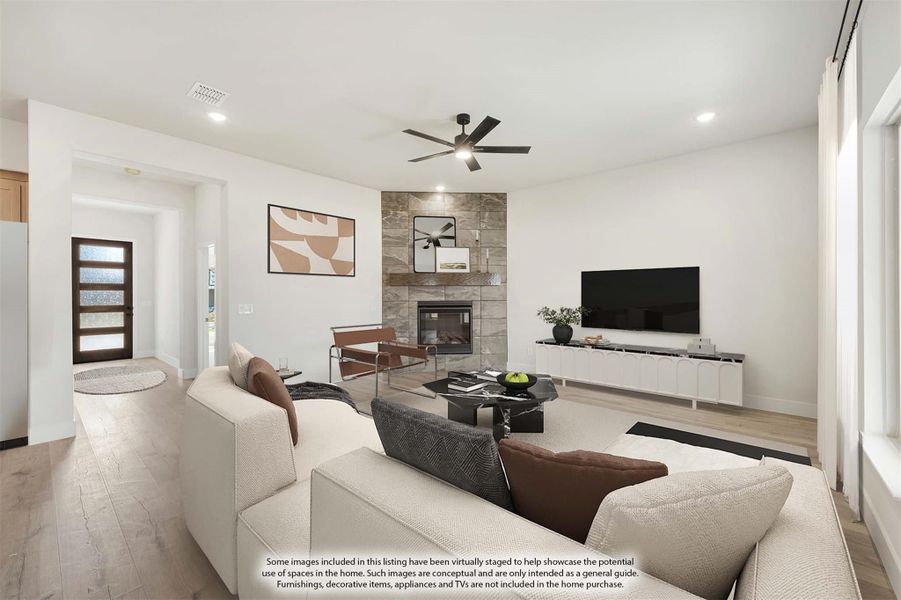 Living room with stone fireplace, ceiling fan, light wood floors, and neutral seating area