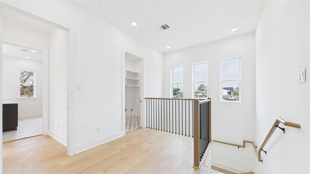Airy upper-level landing with three vertical windows providing natural light. Cozy additional living space.