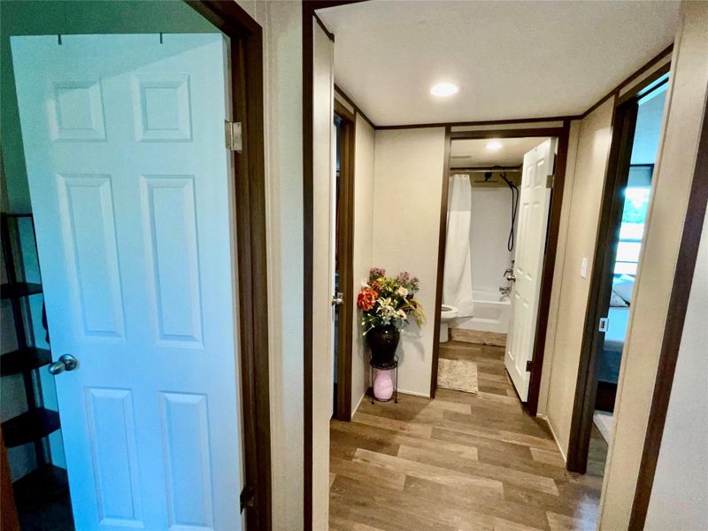 Hallway featuring wood-finish flooring, recessed lighting, and a neutral wall palette with dark trim