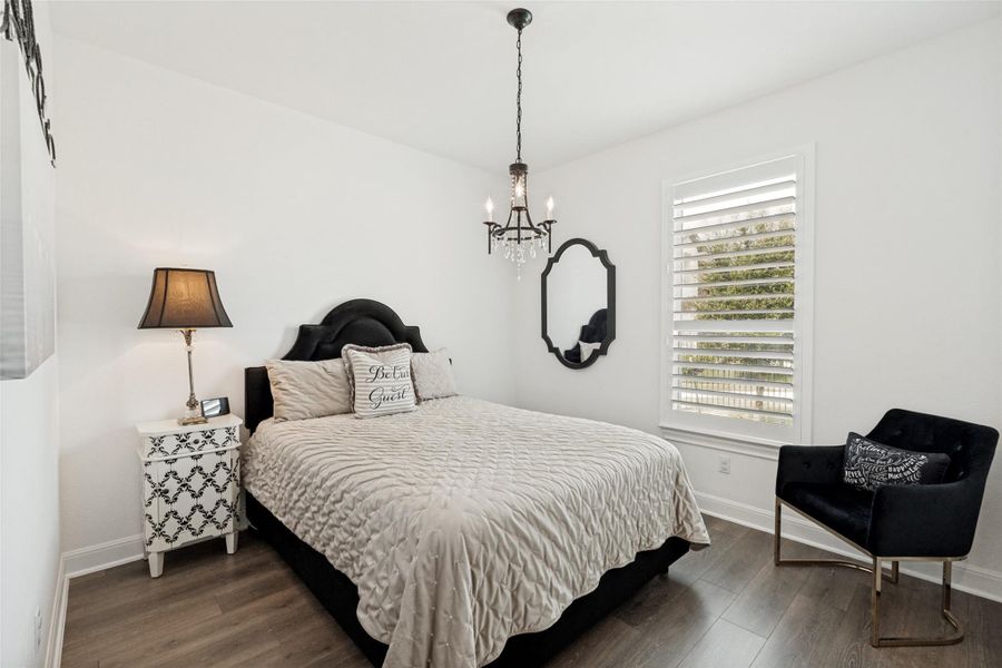 Crisp walls and rich flooring define this calm sleeping space with plantation shutters.